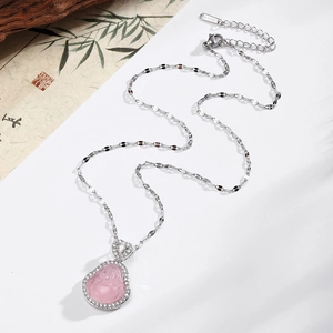 Détail du pendentif Bouddha rose avec chaîne en acier inoxydable sur fond zen élégant