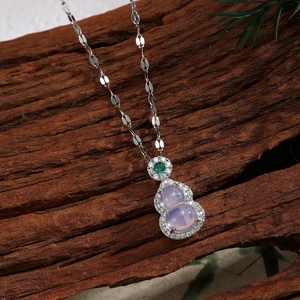 Macro detail of lavender gourd pendant with green gem and crystals on wood texture