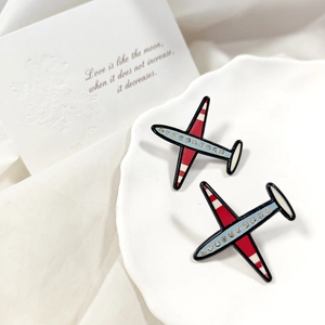 Spille creative a forma di aereo con ali in smalto rosso bianco e strass brillanti sul piatto