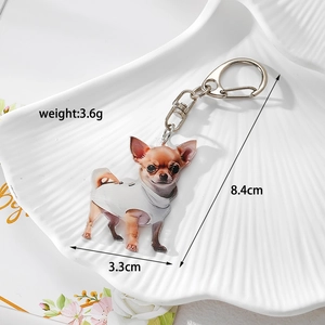 Detail view of acrylic Chihuahua dog keychain with lobster clasp on white shell tray