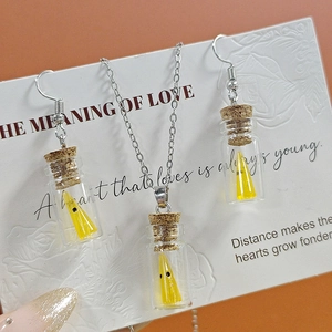 Parure collier et boucles d'oreilles fantôme lumineux dans une bouteille en verre sur fond rouge