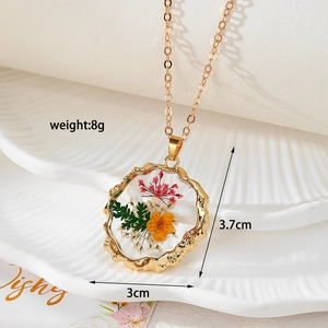 Détail du pendentif en résine avec fleurs, dimensions 3cm x 3,7cm et poids de 8g indiqué