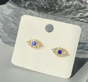 Détail macro de boucles d'oreilles Œil de Turquie dorées avec strass sur carte