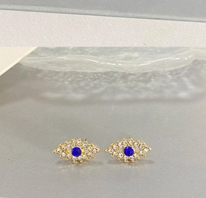 Détail de boucles d'oreilles œil porte-bonheur avec cristal bleu et strass blancs