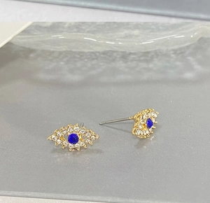 Gros plan de boucles d'oreilles Evil Eye dorées avec pierres bleues et strass blancs