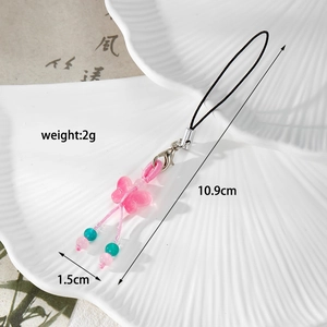 Detailed view of a pink butterfly phone charm with beads and silver lobster clasp