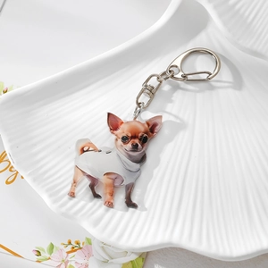 Detail view of a cute Chihuahua acrylic keychain on a decorative white textured tray