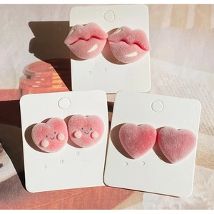 Lot de boucles d'oreilles cœur et lèvres floquées roses sur carte à bijoux blanche