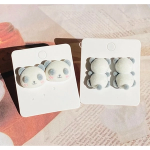 Détail de boucles d'oreilles panda floquées avec texture douce sur une carte de présentation