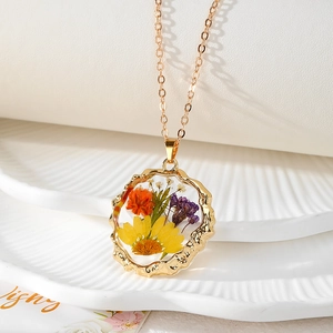 Collier artisanal en résine avec fleurs séchées, pendentif doré irrégulier et chaîne fine