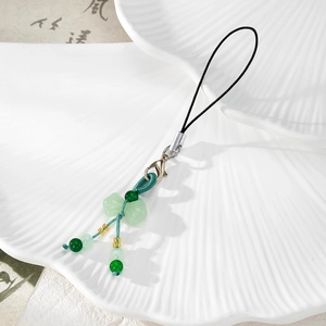 Detail view of a green jade-textured butterfly charm with woven cord and lobster clasp