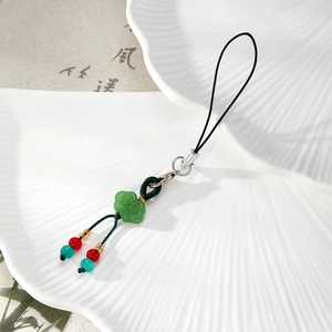Detail of green ruyi knot charm on white ceramic plate with Chinese style tassel and beads