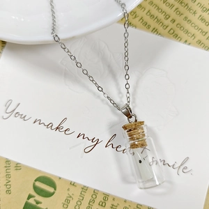 Gros plan d'un collier fantôme lumineux en bouteille de verre sur carte cadeau