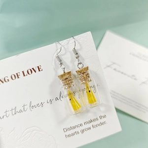 Vue détaillée des boucles d'oreilles bouteille en verre avec une figurine fantôme jaune