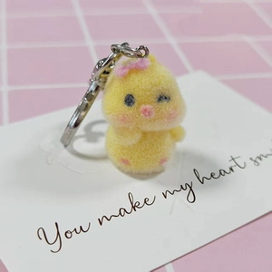 Detail of cute yellow flocked chick keychain with a pink bow on a display card