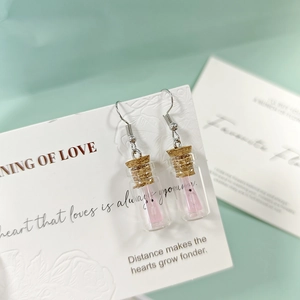 Vue macro de boucles d'oreilles bouteille en verre avec liège et fantôme rose brillant
