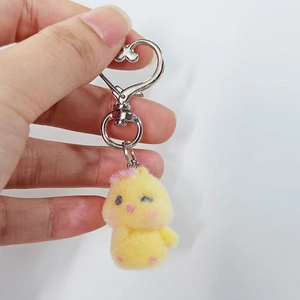Close-up of yellow flocked chick keychain with pink bow and heart-shaped metal hook