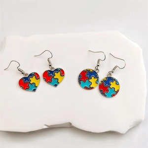 Detail of heart and round enamel puzzle earrings in vibrant red, blue, and yellow colors