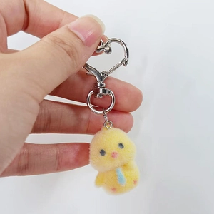 Detailed close-up of yellow flocked chick keychain with a heart-shaped silver metal clasp