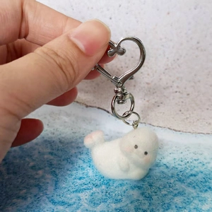 Close-up of white flocked seal keychain with pink blush and heart-shaped metal hook