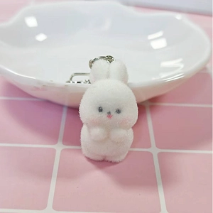 Close-up of white flocked bunny keychain with pink nose on a cute checkered tabletop