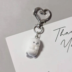 Detail of cute grey plush seal keychain featuring a silver heart-shaped metal clip