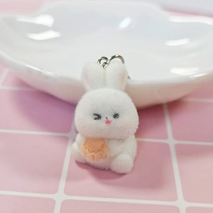 Close-up of a white flocked bunny keychain holding a carrot with a silver metal ring