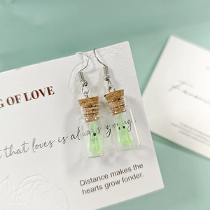 Gros plan de boucles d'oreilles bouteille en verre avec mini fantôme lumineux