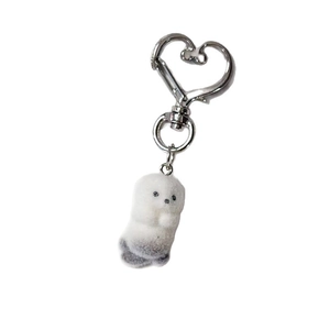 Cute white plush sea otter keychain with a silver heart-shaped metal clip on white background