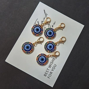Set of 5 Evil Eye pendants with colorful rhinestones and gold lobster clasps on a gift card