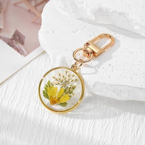 Detailed macro view of a handmade round resin keychain with yellow daisy and dried flowers