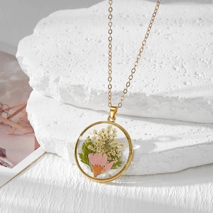 Détail du pendentif rond en résine avec vraies fleurs séchées roses et chaîne dorée