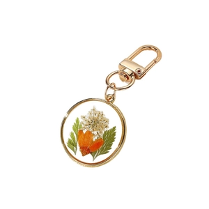 Handmade resin keychain with real dried orange daisy flowers in a gold metal frame