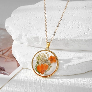 Collier bohème avec fleurs séchées orange et blanches naturelles dans un pendentif en résine