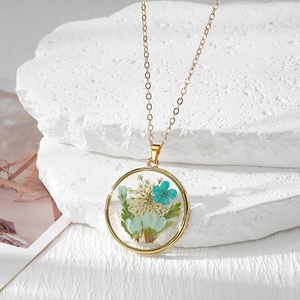 Vue détaillée du pendentif rond en résine avec fleurs séchées et cadre doré