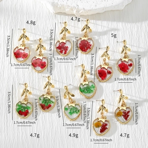 Detail view of handmade resin heart earrings with colorful real dried flowers and gold leaf