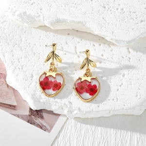 Detail of strawberry-shaped resin earrings featuring real red dried flowers and gold leaves