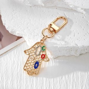 Makroaufnahme von Hamsa-Hand-Schlüsselanhänger mit goldenem Metallnetz und bösen Augen