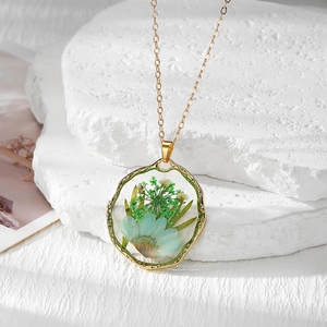 Gros plan détaillé d'un collier bohème doré avec de véritables fleurs séchées bleues et vertes