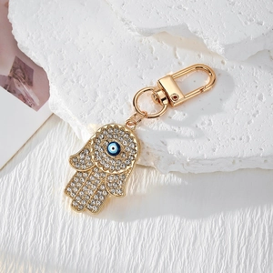 Détail du porte-clés main de Fatma doré avec cristaux blancs et perle bleue de mauvais œil