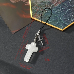 Détail macro du pendentif croix en résine scintillante avec breloque strass et cordon