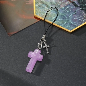 Détail de breloques en résine violette pailletée et croix en métal sur cordon