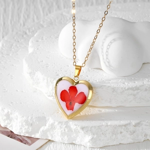 Bohemian gold heart necklace with red dried flower inside on white stone display