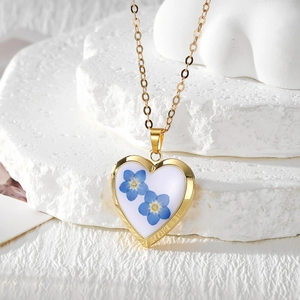 Detailed macro shot of heart-shaped gold locket with blue dried flowers in resin