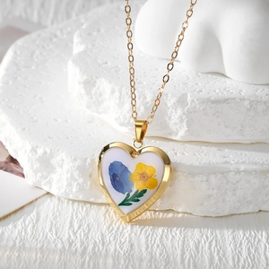 Detail shot of heart-shaped gold locket necklace with colorful dried flower resin patterns