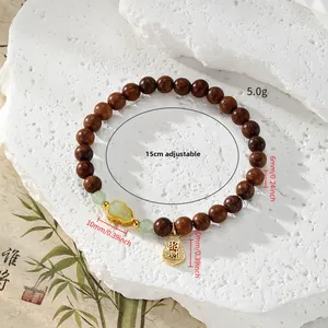 Détail de perles de bois de santal avec jade vert et breloque Pixiu en or sur bambou
