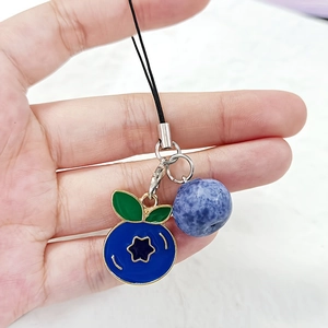 Detailed view of blueberry charms with green leaves on a black cord strap held by hand