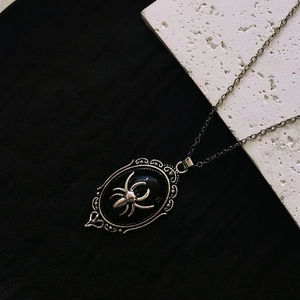 Gothic necklace featuring a silver spider on a black oval pendant with vintage edges