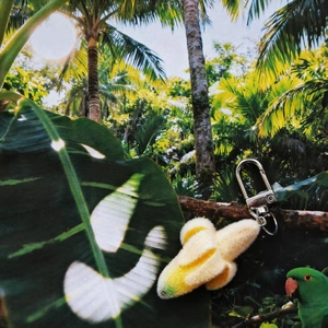 Cute flocked banana keychain with silver metal clip in a tropical forest background