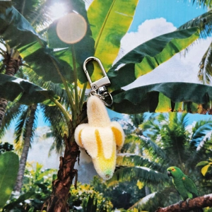 Cute flocked banana keychain pendant with silver metal clasp on tropical summer background